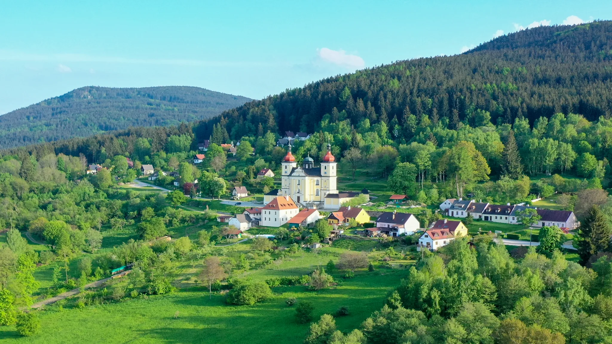 Poutní kostel Panny Marie Těšitelské v Dobré Vodě s kulisou Novohradských hor
