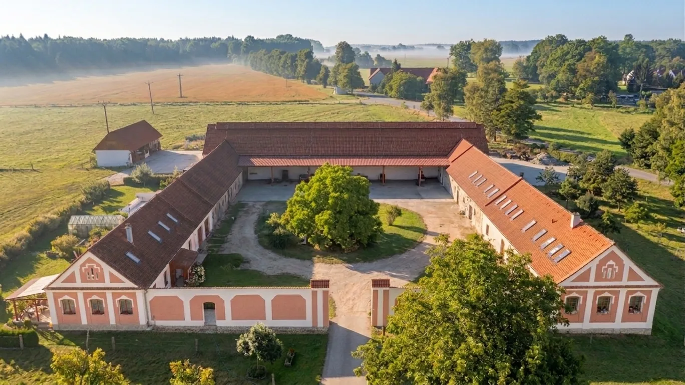 Typický jihočeský statek se zdobnými štíty, zachycující první zlatavé paprsky